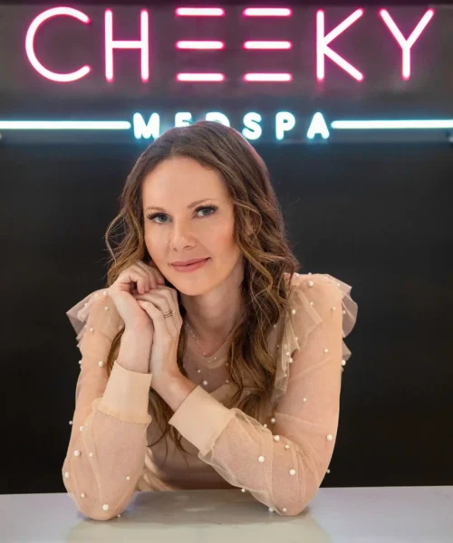 Randi_1n Medical spa professional seated beneath Cheeky Medspa sign in a modern clinic setting