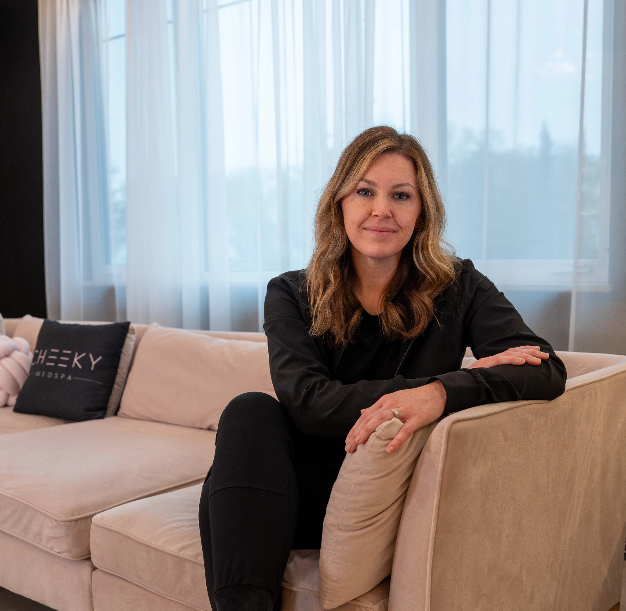 Licensed aesthetic provider seated in a modern medical spa consultation area